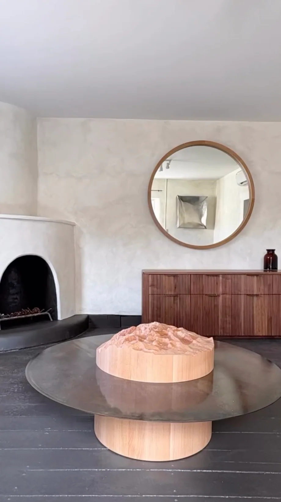 Inside the gallery: fireplace, round mirror and sculptural table